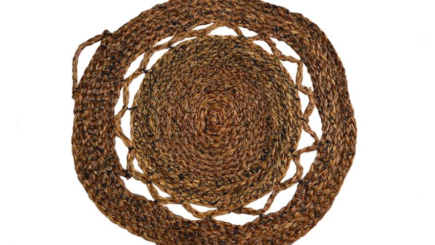 Round woven straw placemat with braided pattern.