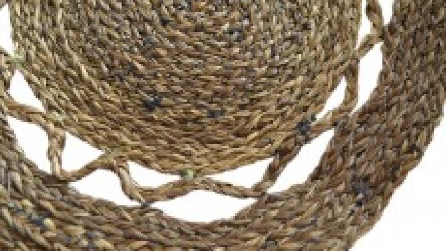 Woven brown straw mat with circular pattern.