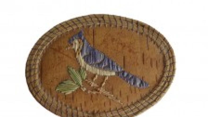 Oval embroidered bird patch with blue and green on a brown background.