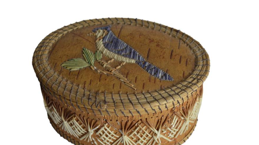 Woven basket with bird design on lid, brown with blue and green accents.