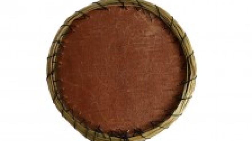 A round hand drum with a brown leather surface and rope binding.