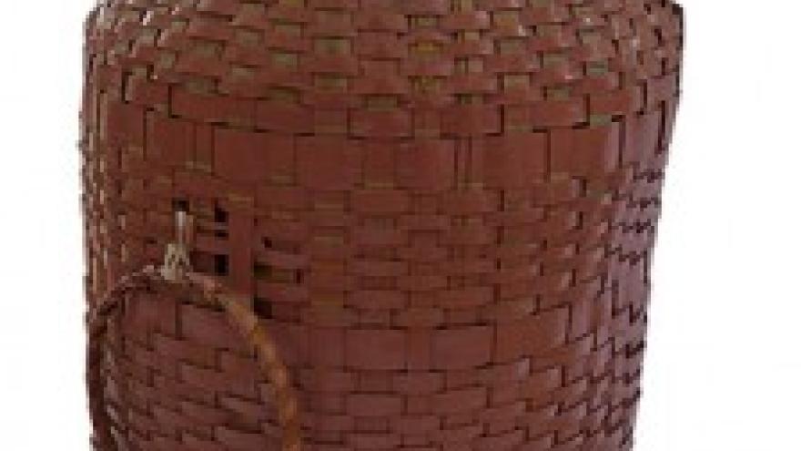 Woven brown basket with a handle on a white background.