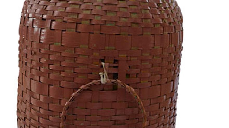Woven brown basket with a lid and circular pattern.
