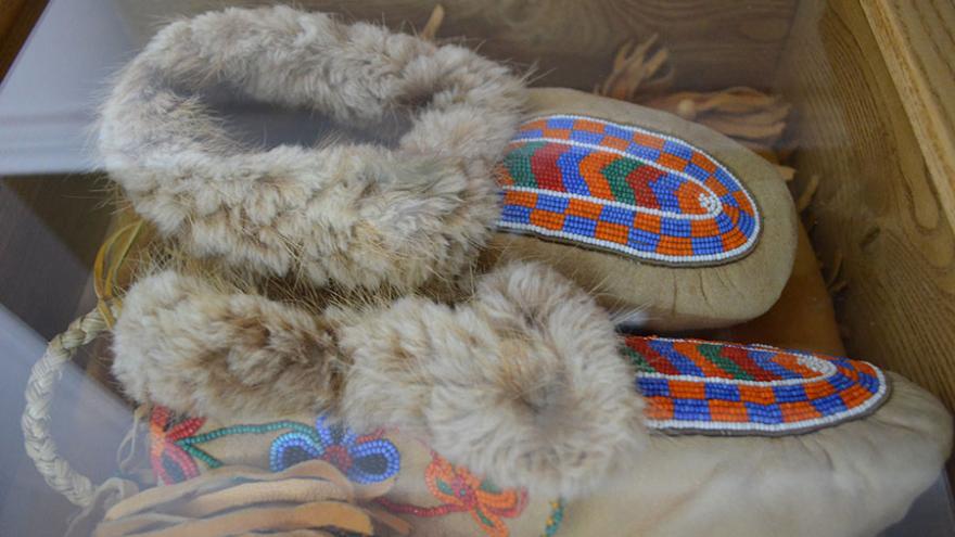 Fur-lined moccasins with colorful beaded design in a wooden box.