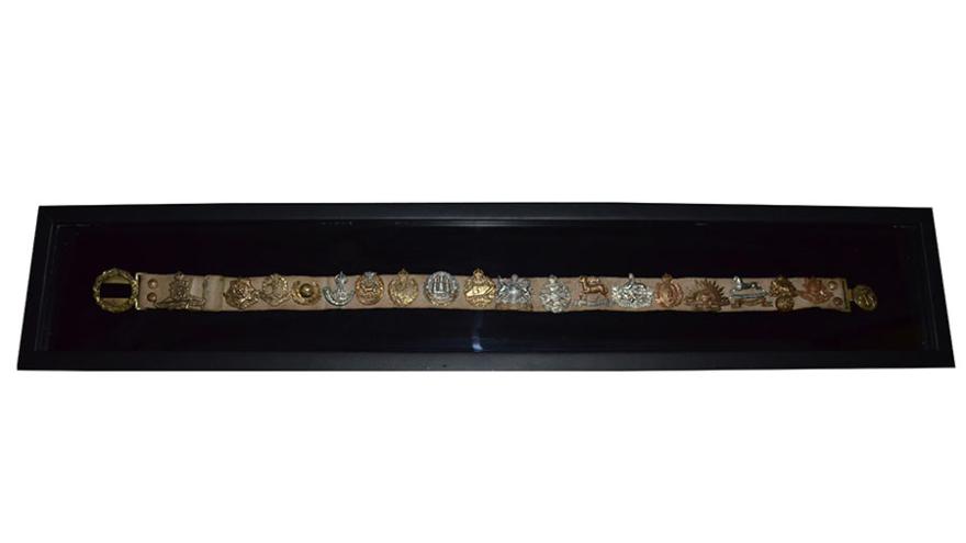 Intricate decorative belt with gold and silver elements, displayed in a black frame.
