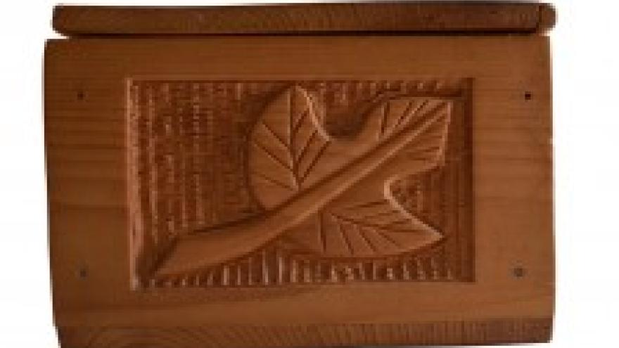 Wooden box with carved leaf design on the lid.