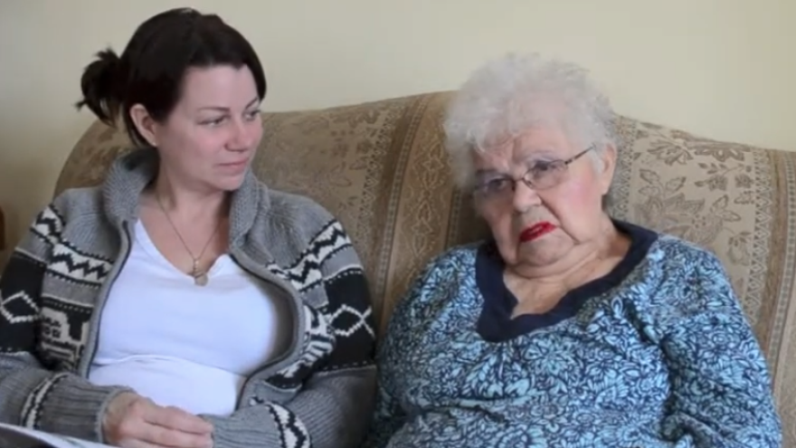 Two women sitting on a couch, one elderly, both with calm expressions.