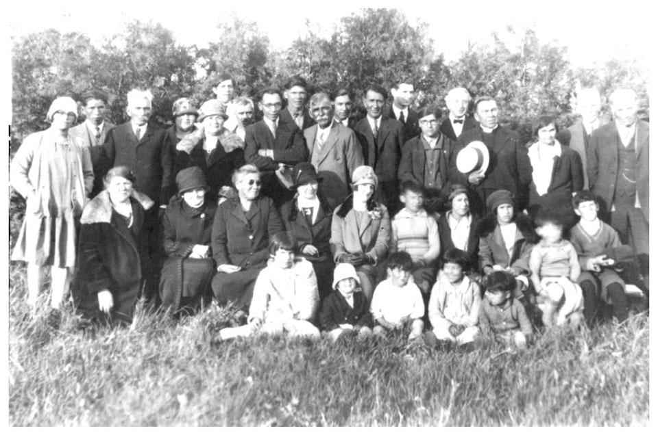 Black and white photo of a large group posing outdoors in a field.