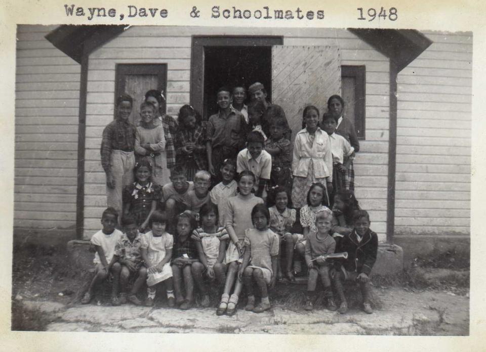 Group of children and adults posing in front of a wooden building, 1948.