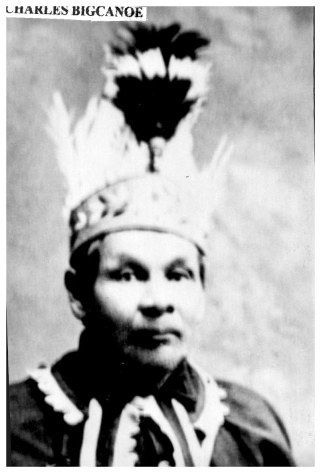 Black and white photo of a person wearing a feathered headdress.