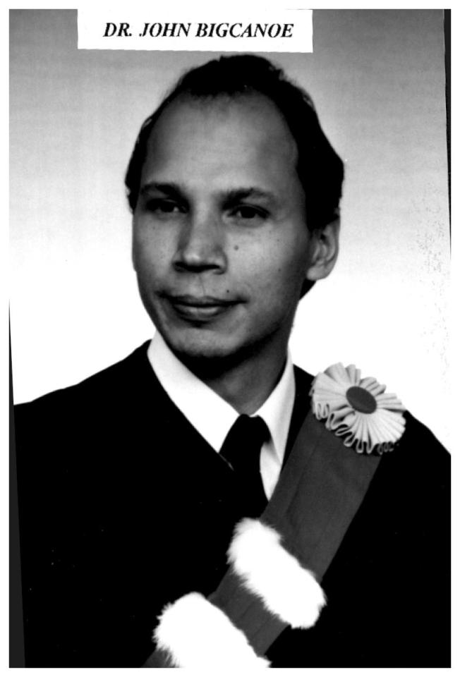 Black and white portrait of a man in a suit with a floral sash.