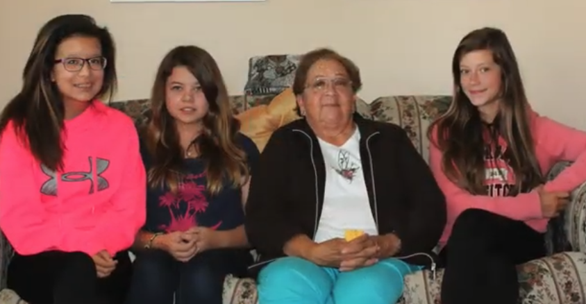 Four people sitting together on a couch, smiling warmly.
