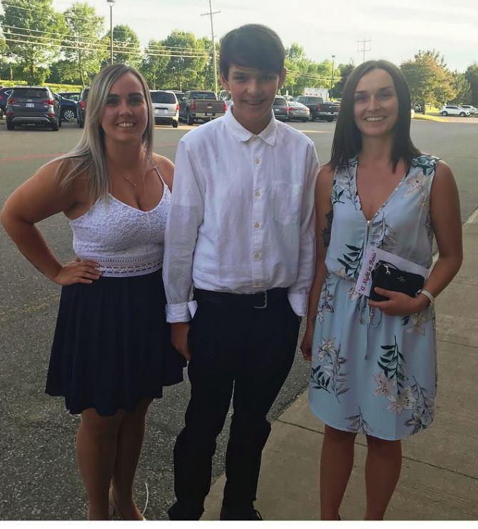 Three people posing outdoors, two women and a young person dressed nicely, smiling.